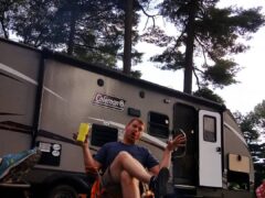 Man sitting in front of brown travel trailer